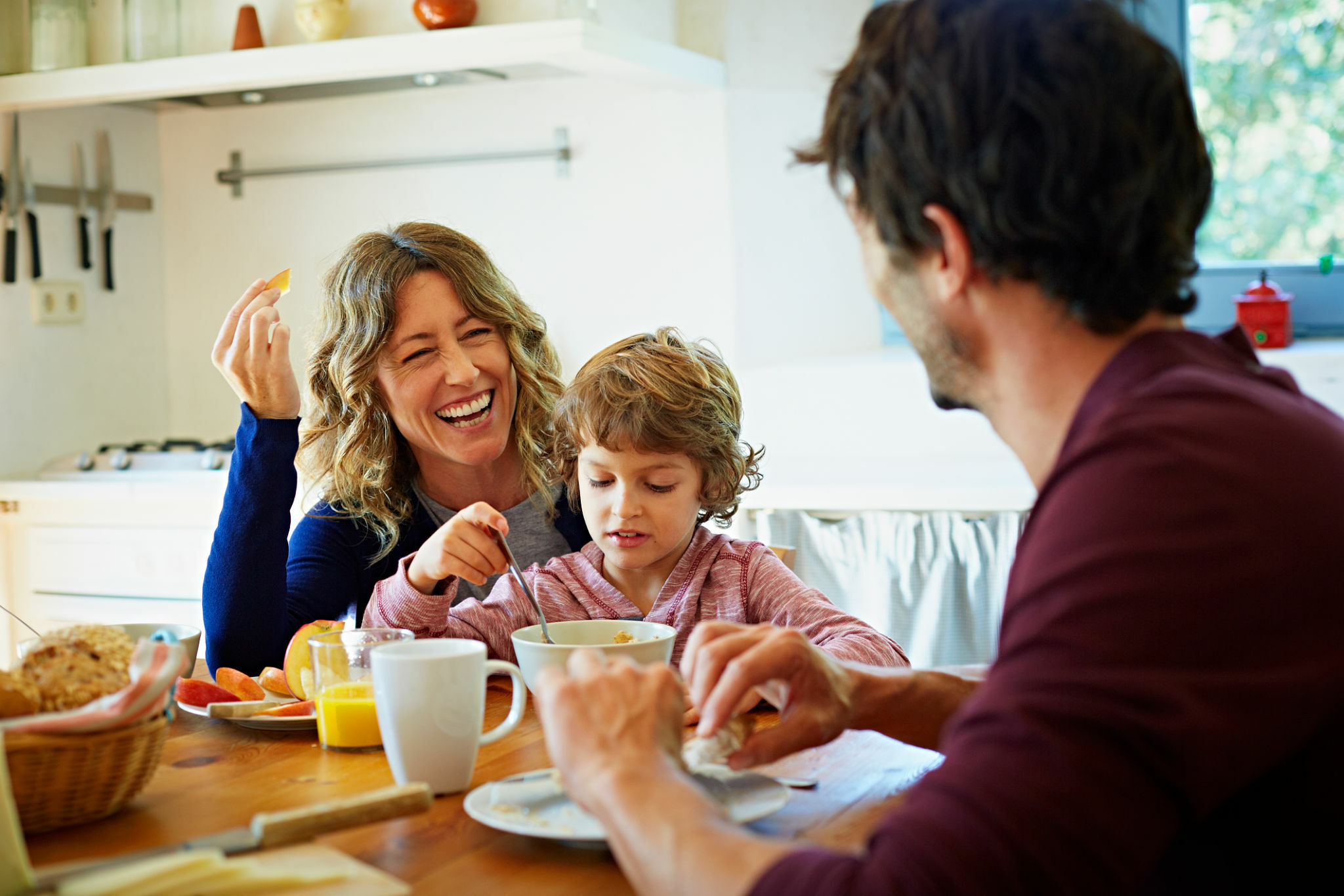 Happy family of three enjoying breakfast at sheenas table in domestic kitchen