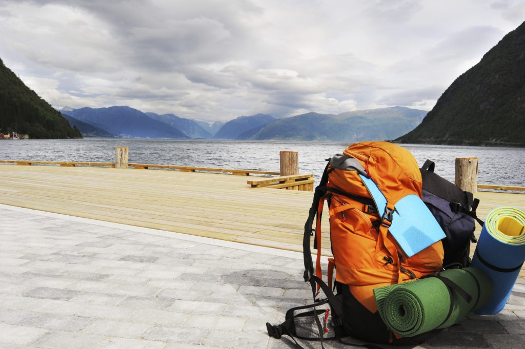 Tourists backpack on a pier in Norwegian fjords